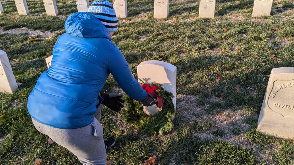 Person laying wreath at gravestone